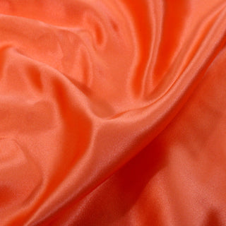 close-up of coral colored silk charmeuse, detailing the satin weave and high-shine