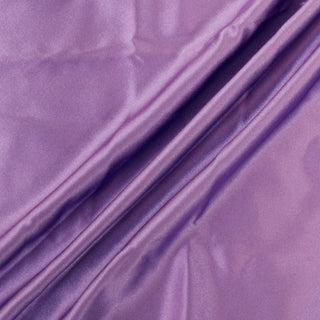 three draping lines arranged of a piece of light purple silk charmeuse fabric, demonstrating its high shine, soft drape, and lightweight hand