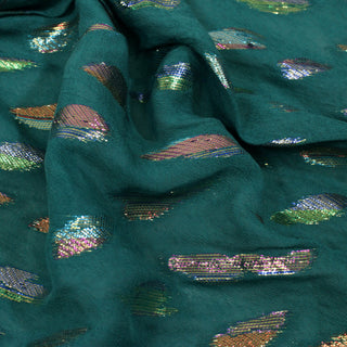 close-up of rainbow sparkle lurex patterned emerald colored fabric