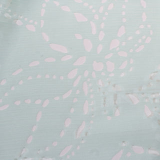 flat lay of seafoam colored eyelet crinkle chiffon fabric, detailing the botanical cutout print on the fabric
