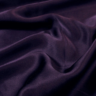 close-up of eggplant colored silk mikado fabric, detailing its qualities