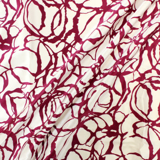 three diagonal lines draped of a mulberry and white colored abstract patterned silk mikado fabric