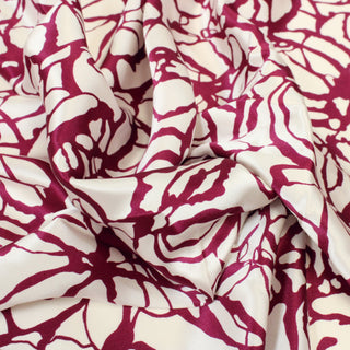 close-up of an abstract printed mulberry and white colored silk mikado fabric