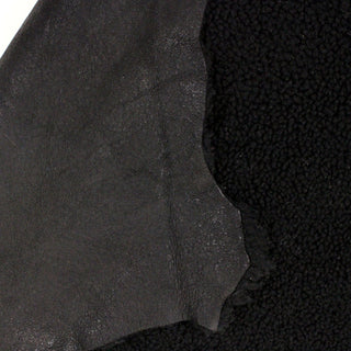 front and backside of a black sheepskin shearling leather hide, short curly piles on the face and black leather backing