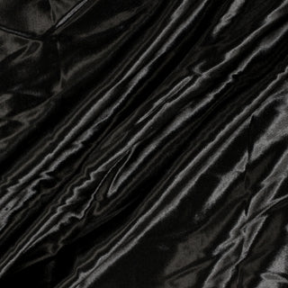 diagonal lines draped of a black charmeuse fabric, detailing its fluid drape and high-shine quality