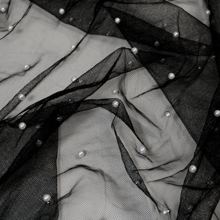 close-up of black mesh fabric with white faux pearl beads secured to it