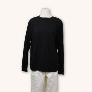 front view of black crew neck sweater. sweater is on mannequin and the mannequin is also dressed in baggy white pants
