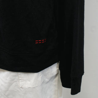 small red lines of embroidery on left hip of black crew neck sweater