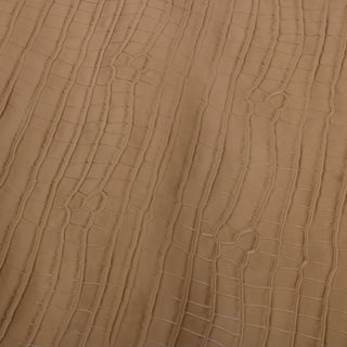 embossed face of a cowhide leather piece in a blonde brown with a crocodile pattern texture and subtle gloss