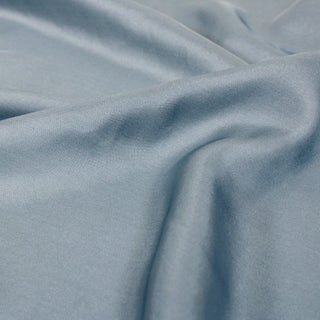 close-up of a bluebell colored silk mikado fabric, detailing its shiny face, soft drape, and twill weave