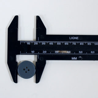 blue plastic button with a button measuring device around it, showing that the button is size 24L