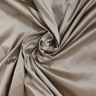 swirl of champagne colored silk taffeta fabric, demonstrating its stiff hand