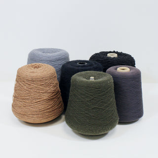 six varying cones of yarn in dark neutral colors