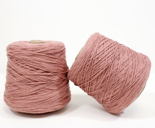two cones of dusty rose colored yarn of varying thickness