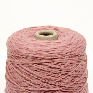 close-up of a spool of dusty rose colored yarn of varying thickness