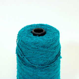 close-up of a small cone of emerald colored eyelash yarn, detailing its texture