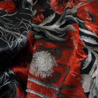 close-up of a red, black, and silver floral silk jacquard fabric, detailing its complex weave structure and subtle surface shine