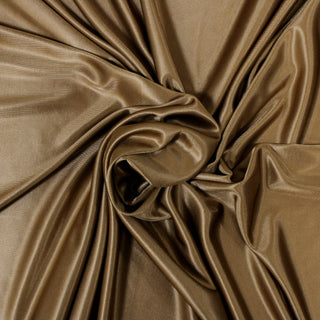 swirl of gold interlock viscose jersey fabric demonstrating its slinky drape
