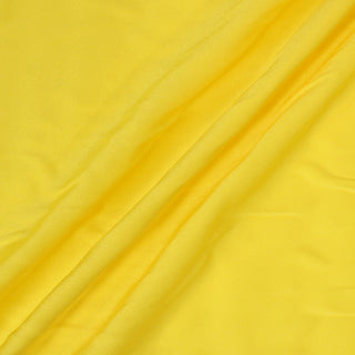 lemon yellow colored crepe back satin fabric arranged with three diagonal peaks to demonstrate its lightweight drape and slightly shiny quality