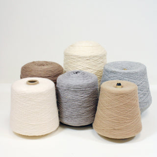 six varying cones of yarn in light neutral colors