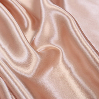 close-up of light pink colored charmeuse fabric, detailing its weave and high-shine face