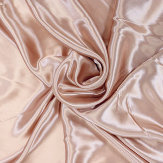swirl of light pink colored charmeuse fabric, demonstrating the soft yet structured drape