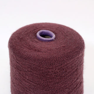 close-up of a cone of mulberry colored machine knitting yarn with a fine-gauge and fuzzy texture