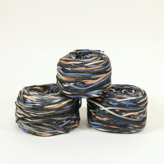 three balls of black and multicolor ribbon yarn in a pyramid