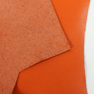 detail shot of vibrant orange cowhide, showing both sides: face a smooth nappa leather, back a rough suede in a lighter orange