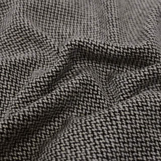 close-up of black and white mini-herringbone suiting fabric, showing its textural weave and subtle drape