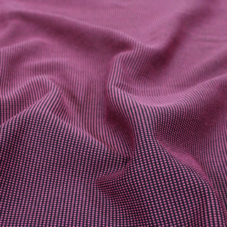 close-up of double-knit jersey fabric, showing in detail that the face of the fabric is black with little pink v-stitches on it
