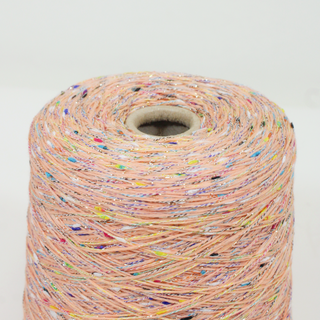 close-up of a cone of lightweight salmon yarn with multicolor flecks and lurex filament