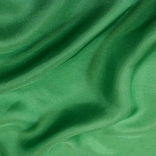 close-up of a seaweed green colored silk mikado fabric, detailing its twill weave and subtle surface sheen