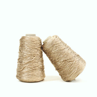 two small cones of fine-gauge wheat colored eyelash yarn with a subtle sheen to its pile