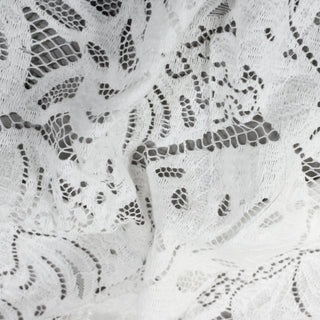 close-up of white botanical lace fabric against a grey background