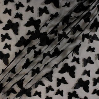 3D black butterfly mesh fabric with gold foil edges on the butterfly. the fabric is draped in three diagonal lines to show the dimension and hand