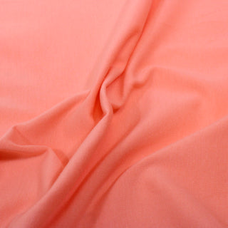 close-up of a coral colored jersey fabric, detailing the knit structure and soft, lightweight drape