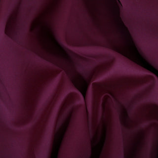 Close up of eggplant purple bengaline fabric, detailing the surface shine and drape.