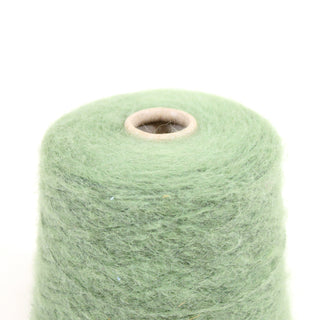 Closeup of green mohair yarn cone on a white background, detailing the texture.