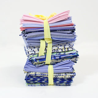 stack of packs of fat quarter quilting fabrics, 10 fabrics per pack which are tied with a yellow ribbon