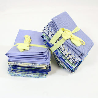 two stacks of blue and white fat quarter quilting fabric packs, each tied with yellow ribbon