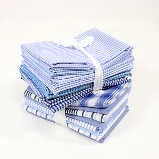 stack of two half-yard packs of 10, of blue and white quilting fabrics in a variety of patterns, tied up with white ribbon
