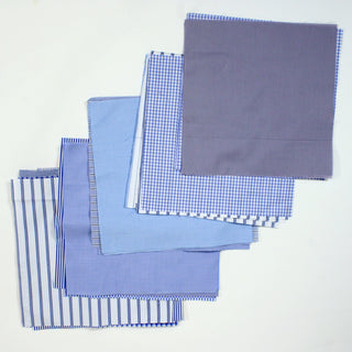 layer cake quilting fabric pack in blue and white, arranged into five piles of overlapping squares to show the variety of fabric patterns