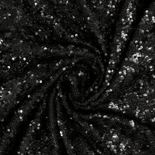 swirl of a black sequin tweed fabric, demonstrating the drape and shine of the fabric