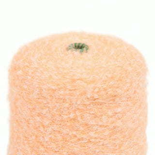 Closeup of peach color loop yarn on a white background, detailing the texture