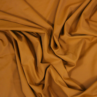 Close up of an orange jersey fabric, detailing the drape and surface shine.