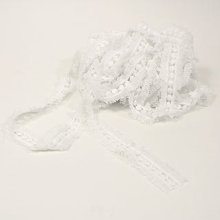 a ball of white eyelash-dot ribbon trim on a white background