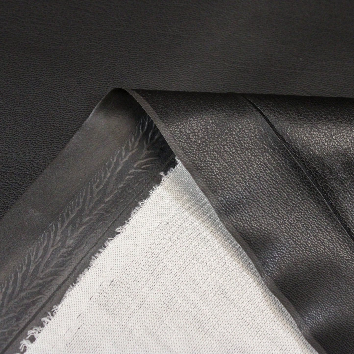 close-up of black pleather front and back showing white knit backing